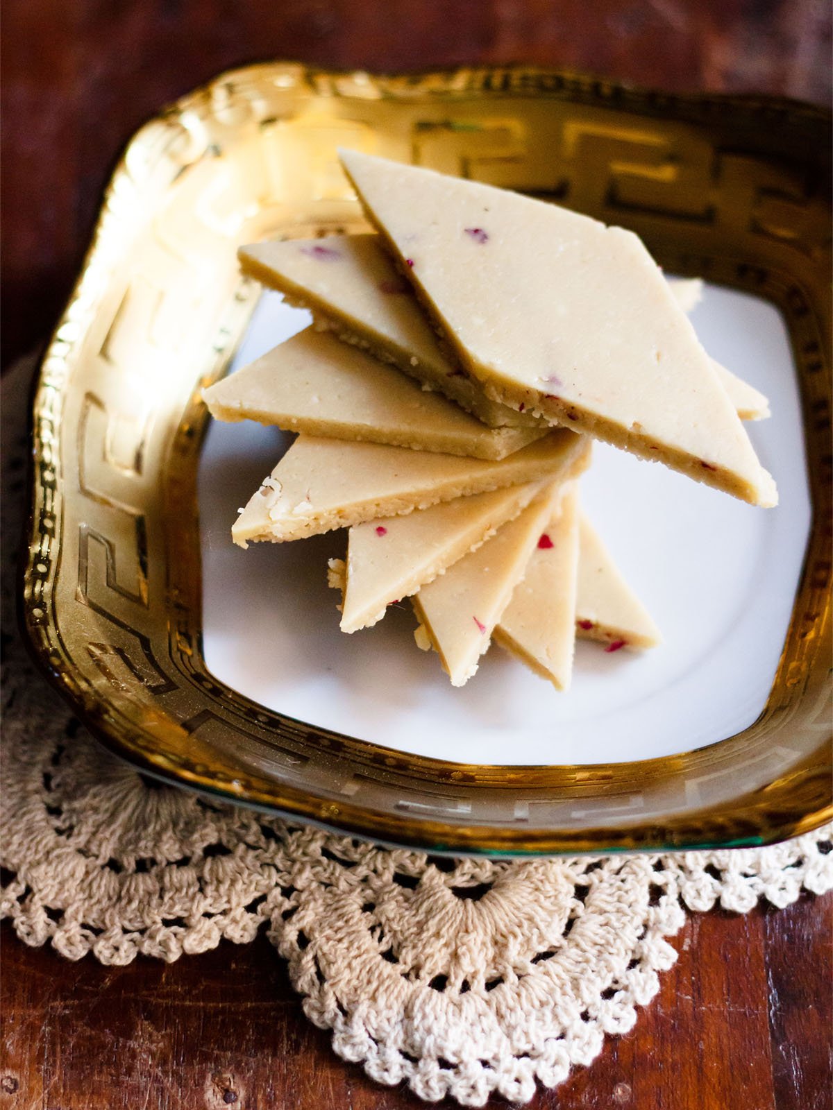 kaju katli stacked spirally on a golden rimmed white square plate