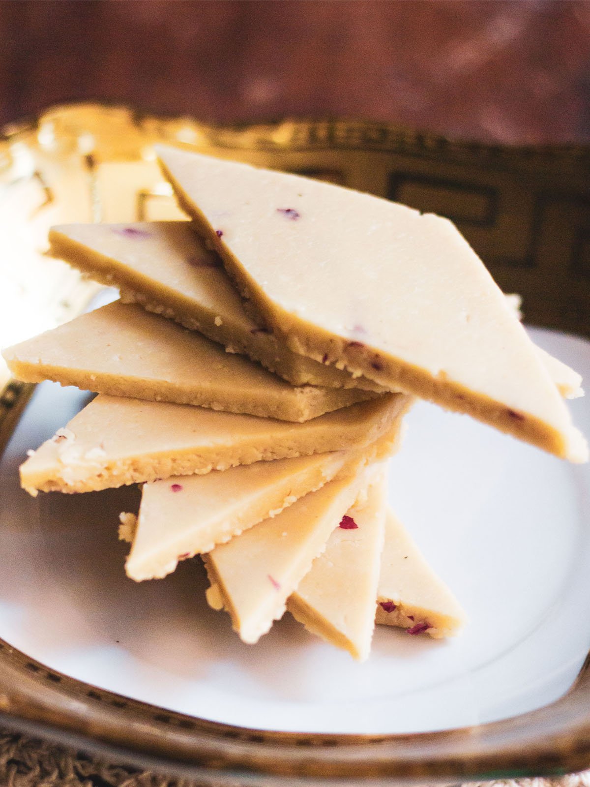 kaju katli stacked spirally on a golden rimmed white square plate