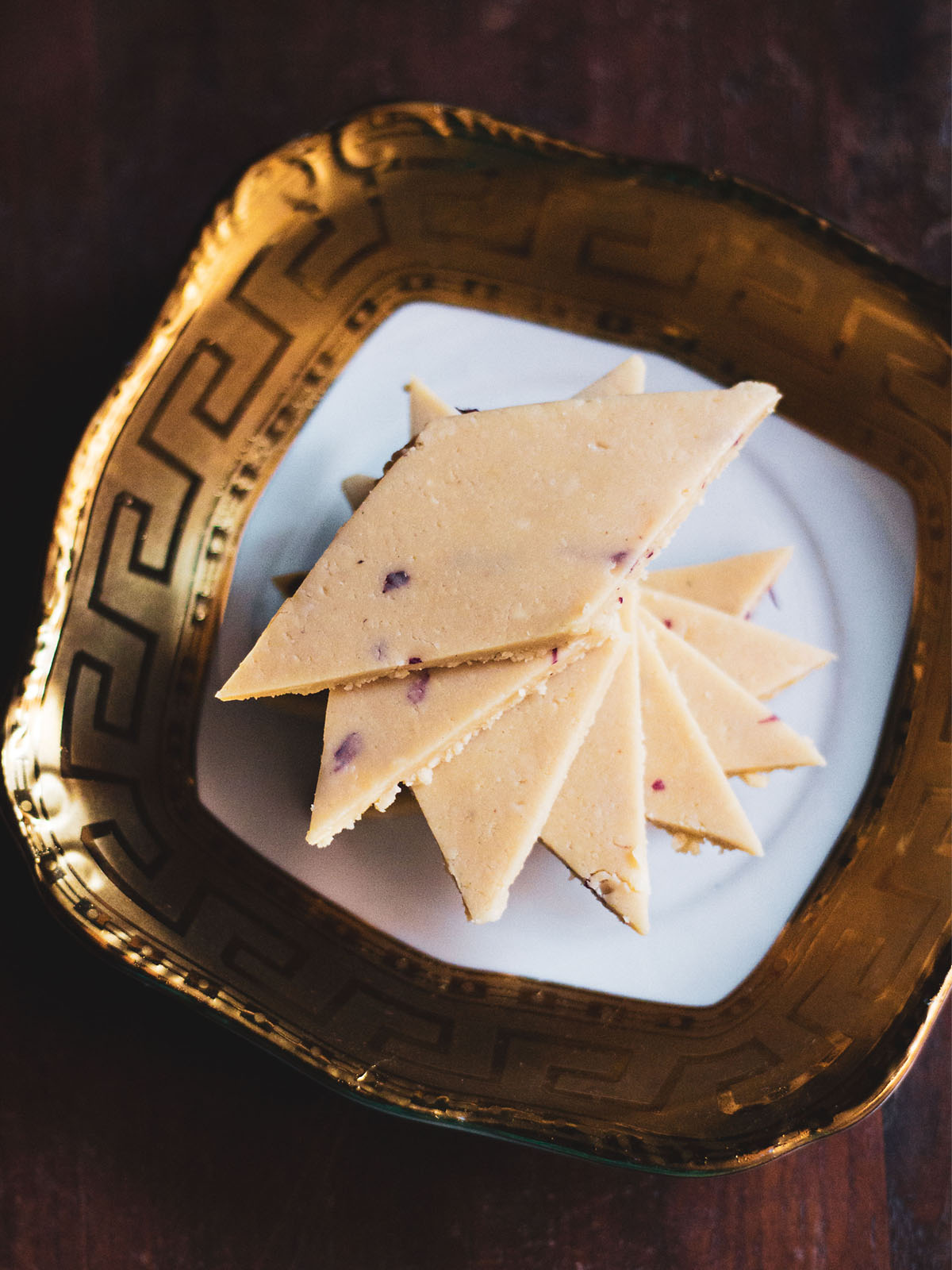 kaju katli stacked spirally on a golden rimmed white square plate