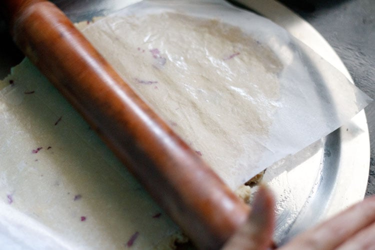 rolling the dough with parchment paper kept on top of dough