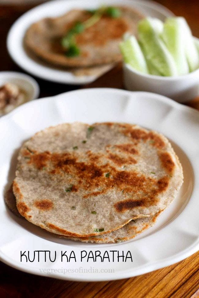 kuttu ka paratha served on a white plate with a side of peanuts cucumber and raita.