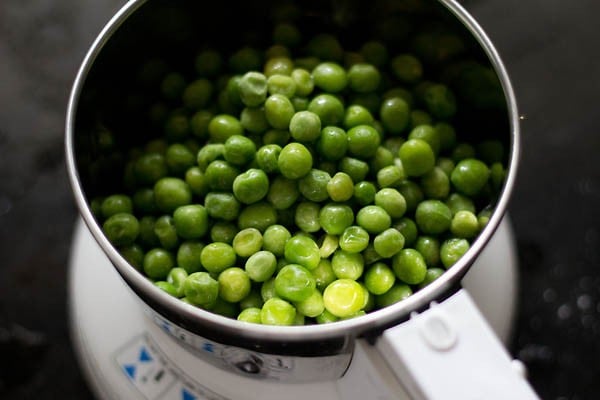 green peas, ginger and green chilies added to a grinder jar for making stuffing for motor shutir kochuri.