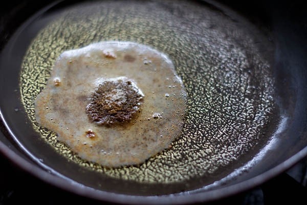 frying spice powders in hot oil in a pan for making stuffing for motor shutir kochuri.