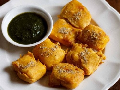paneer pakora served in a white plate with green chutney in a small white bowl.