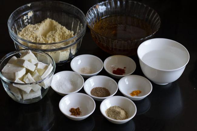 paneer pakora ingredients kept in various bowls on a black background