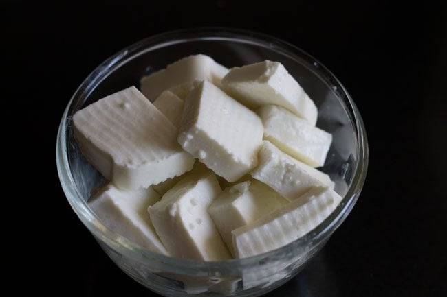 slices of paneer squares in a glass bowl