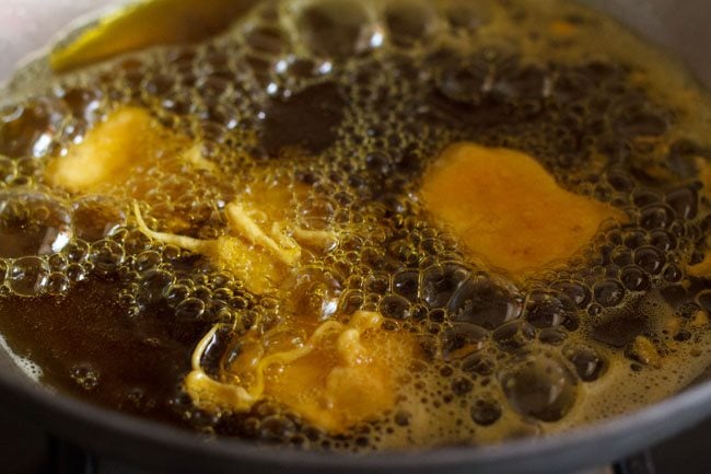 batter coated paneer pakoda getting fried in shimmering mustard oil