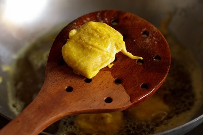 fried, crisp paneer pakora on a wooden slotted spoon