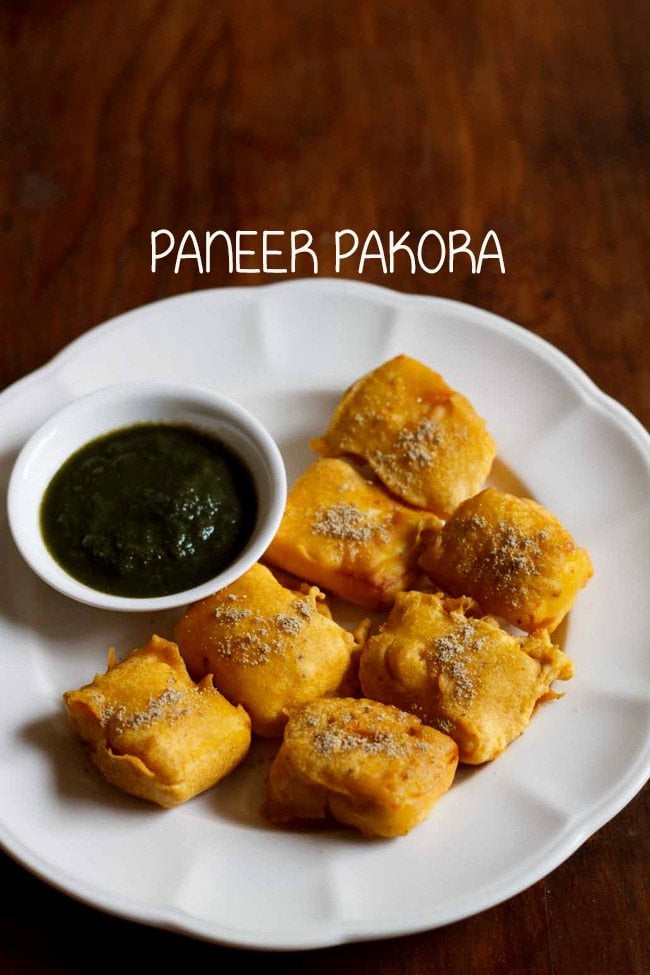 paneer pakora served in a white plate with green chutney in a small white bowl