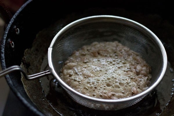 frying poha in a wired mesh strainer to make namkeen recipe