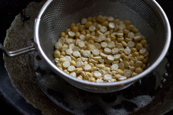 chana dal frying in oil in mesh strainer