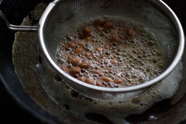 peanuts frying in mesh strainer in hot oil