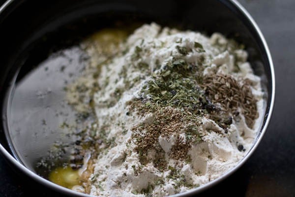 flour, melted ghee and spices for mathri recipe in a mixing bowl