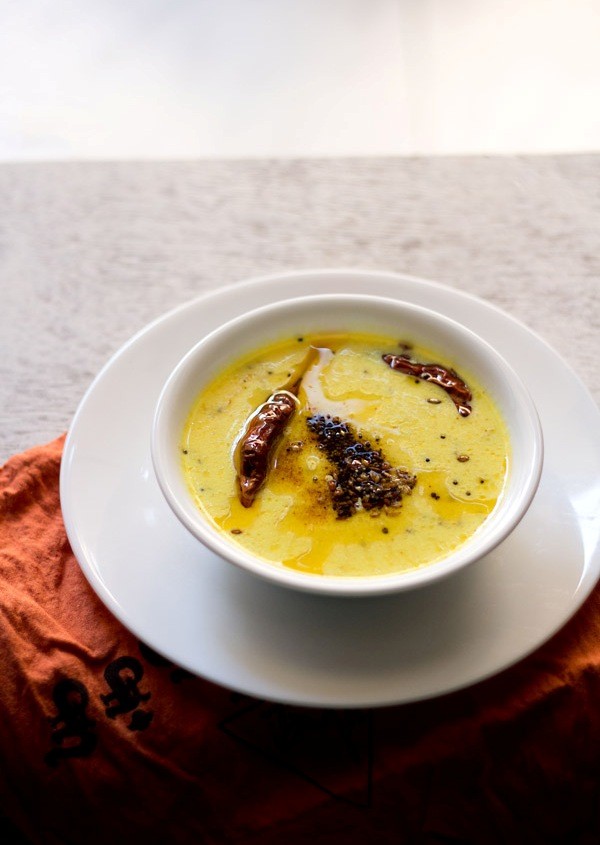 rajasthani kadhi served in a white bowl placed on top of a white plate. 