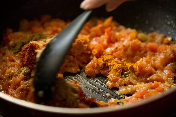 spice powders being mixed with a black spoon