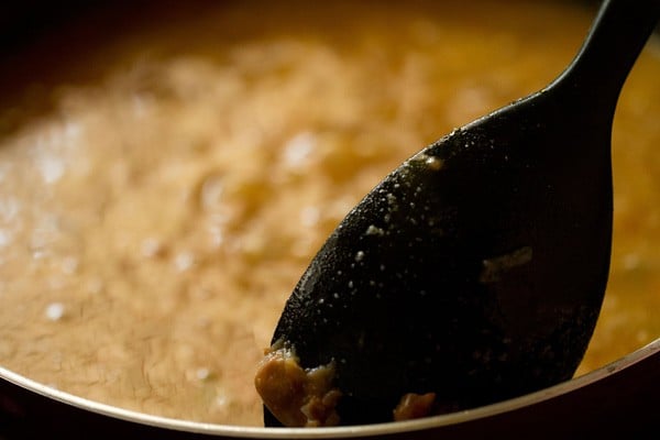 mashing some kidney beans with a spoon in the frying pan itself