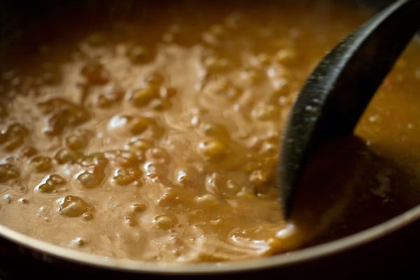 stirring rajma masala with a black spoon