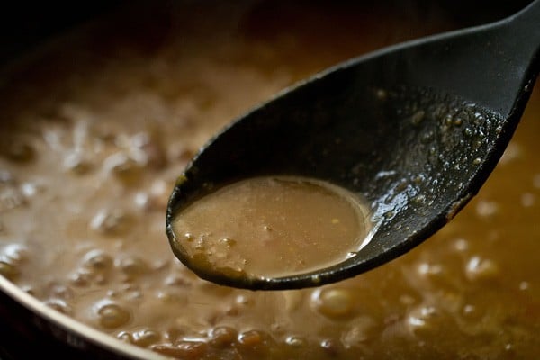 spoon showing the consistency of the rajma masala 