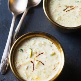 rice kheer served in individual bowls with 2 spoons kept on the upper left corner and text layovers.