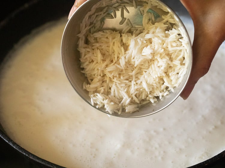 adding rice to boiling milk in the saucepan. 