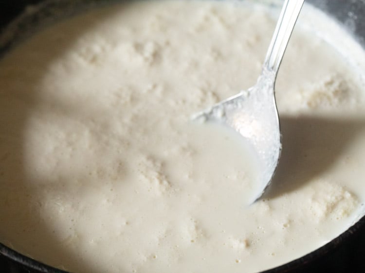 mixing sugar in the milk using a spoon. 