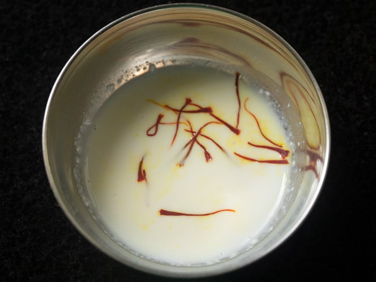 saffron strands added in some milk in a bowl. 