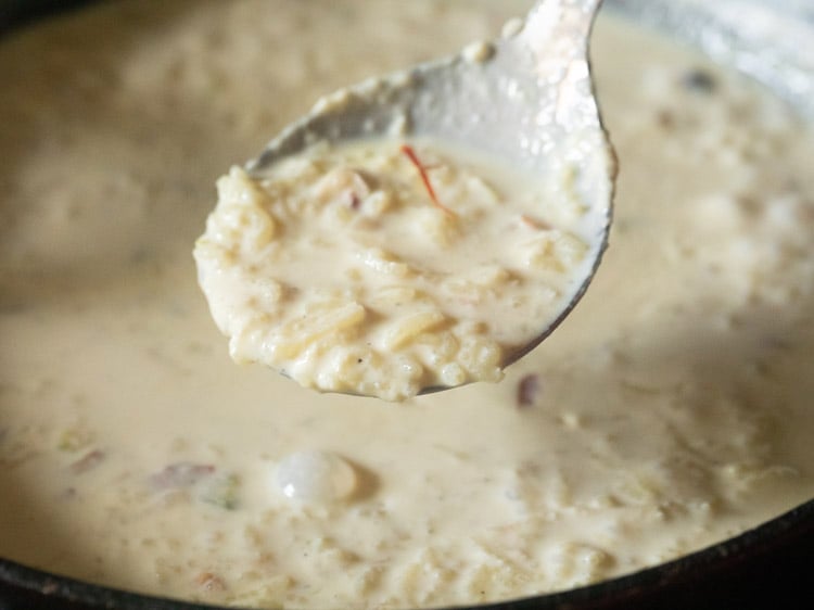 cooked kheer in a spoon. 