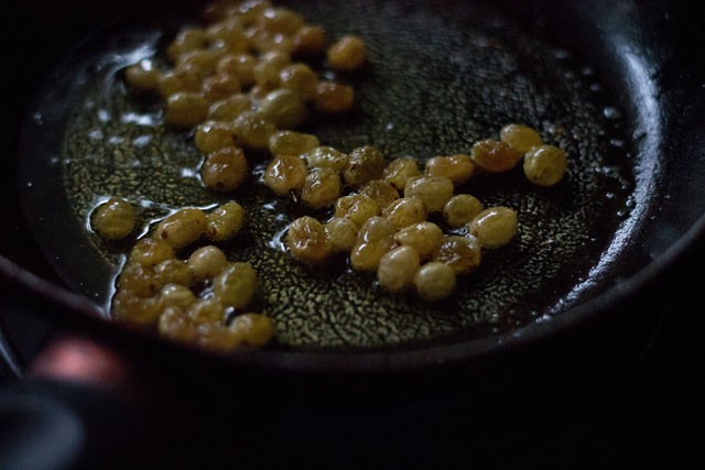 frying raisins in hot ghee. 