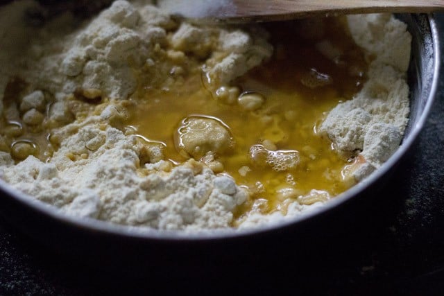 melted ghee added to ground chana dal-sugar mixture. 