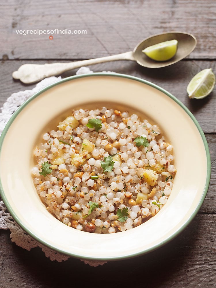 sabudana khichdi served in a green rimmed cream colored plate.