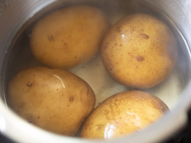 cooking potatoes in a pressure cooker for sabudana khichdi recipe.