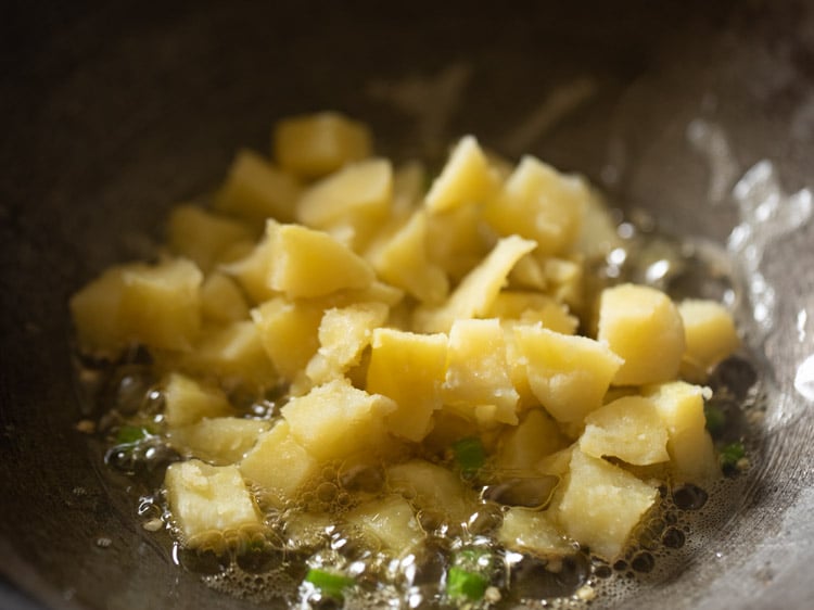 khối khoai tây luộc xắt nhỏ thêm vào chảo.