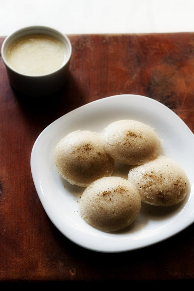 sama chawal idli served on a square white plate with a small bowl of coconut chutney kept on the top left side.