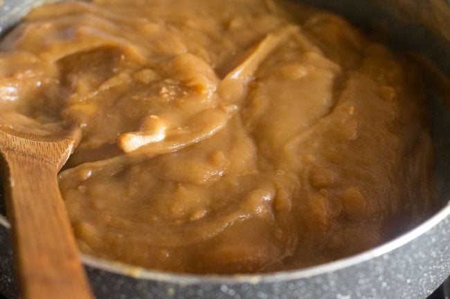 mixing fried cashews into the wheat halwa that is thickening. 