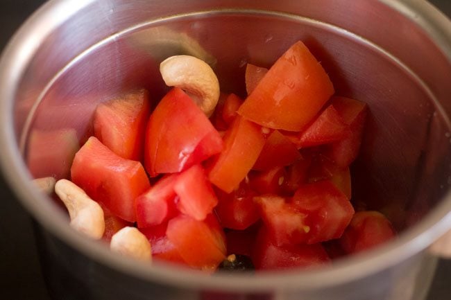 chopped tomatoes and cashews in a grinder jar