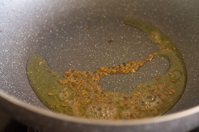 crackling cumin seeds in a kadai in oil
