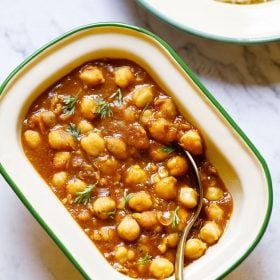 Instant Pot Chana Masala served in a rectangular enamel cream bowl with a green border with a brass spoon inside the bowl