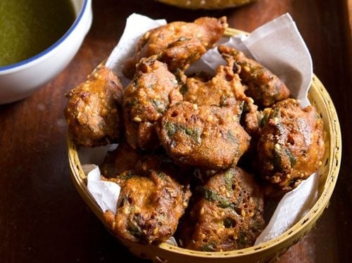 palak pakoda served in a bowl on a wooden board.