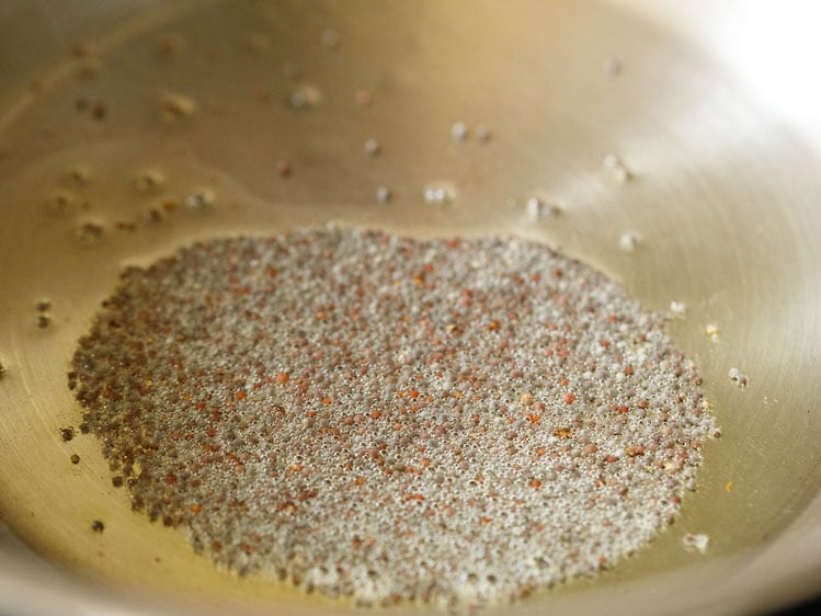 mustard seeds spluttering in hot ghee in pan for making suji ki idli. 