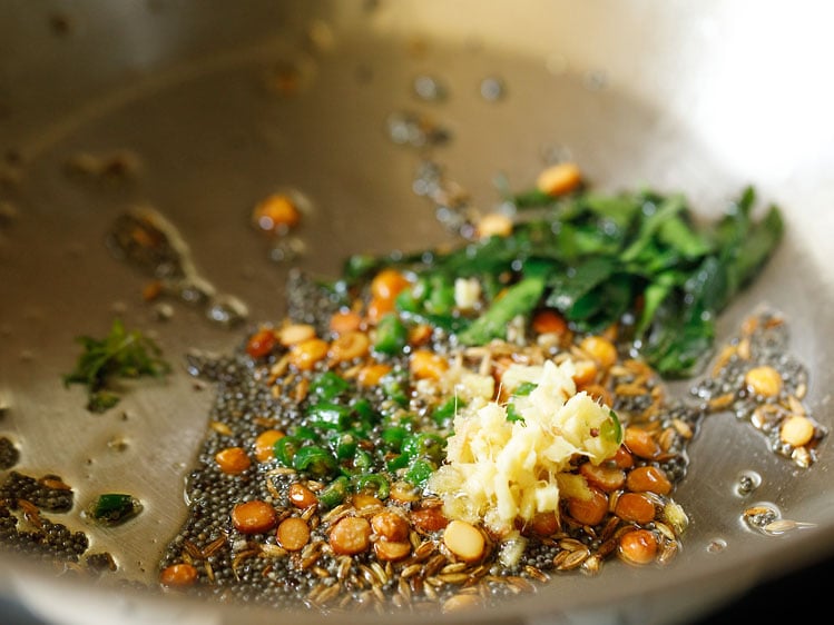 chopped curry leaves, asafoetida, finely chopped ginger and finely chopped green chili added in pan for making suji ki idli. 