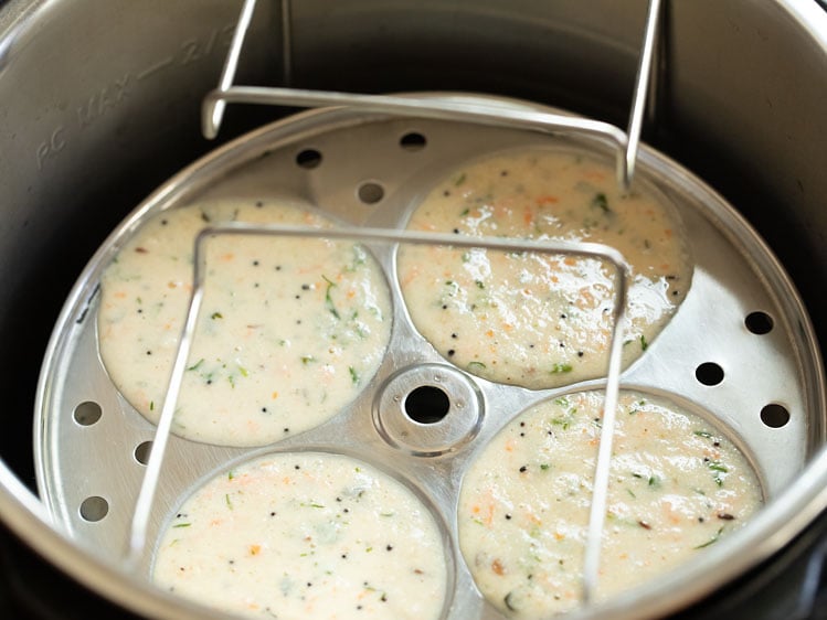 placing idli plates in the pot with hot water for steaming. 