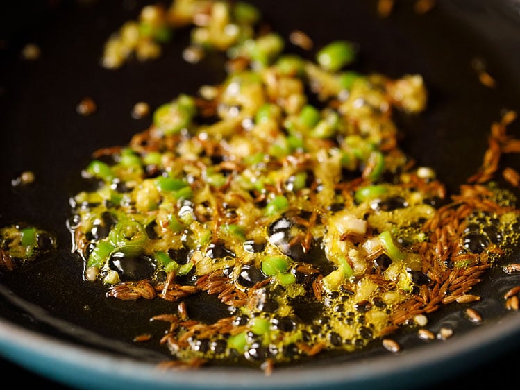 hot oil with cumin seeds, ginger, and green chillies getting fried