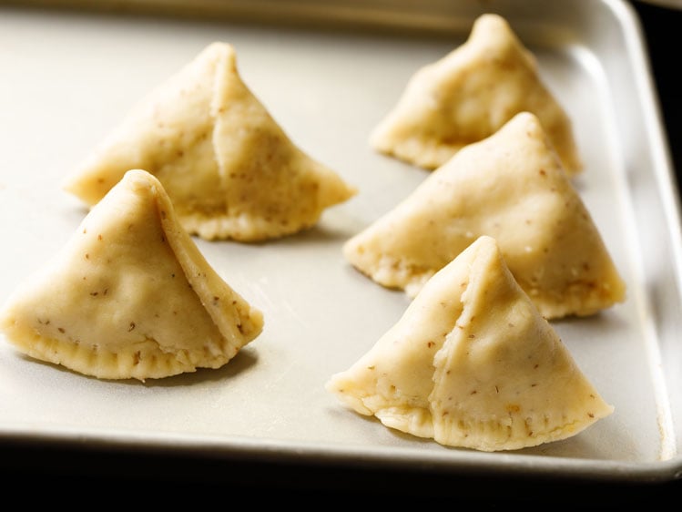 uncooked samosa shaped and kept on a silver tray