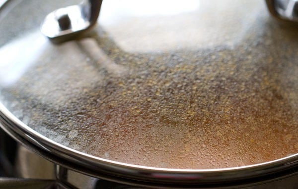 lid completely covering the pan to simmer potatoes and peas