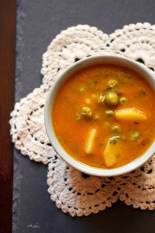 aloo matar gravy in a white bowl on a white crocheted doily