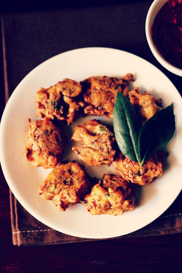 cabbage vada with a two leaf sprig of curry leaves served on a white plate 