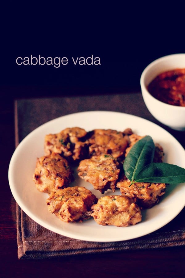 cabbage vada with a two leaf sprig of curry leaves served on a white plate with tomato chutney in white bowl in the background