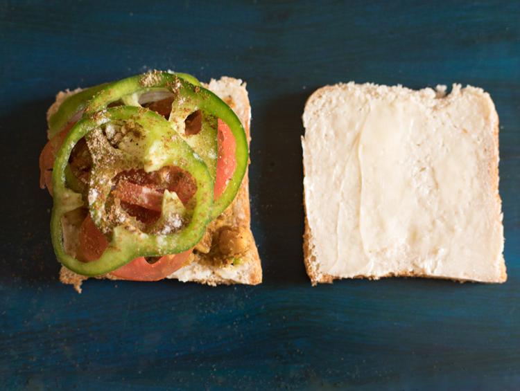 spice powders and salt sprinkled on vegetables for making chana sandwich.