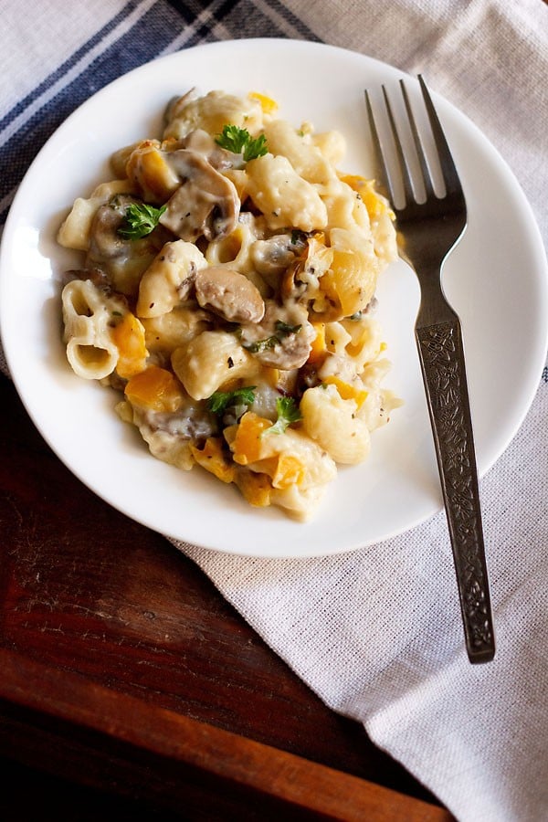 mushroom pasta served in a white plate with a steel fork at the side