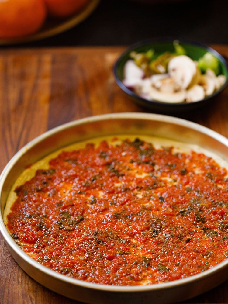 pizza sauce spread on a rolled pizza dough